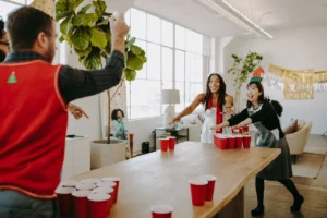 Group of friends playing beer pong at a party table with red cups and ping pong balls