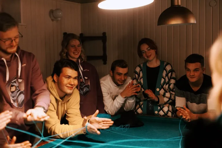 A vibrant, friendly group of people sitting together, laughing and talking, with speech bubbles around them showing question marks.